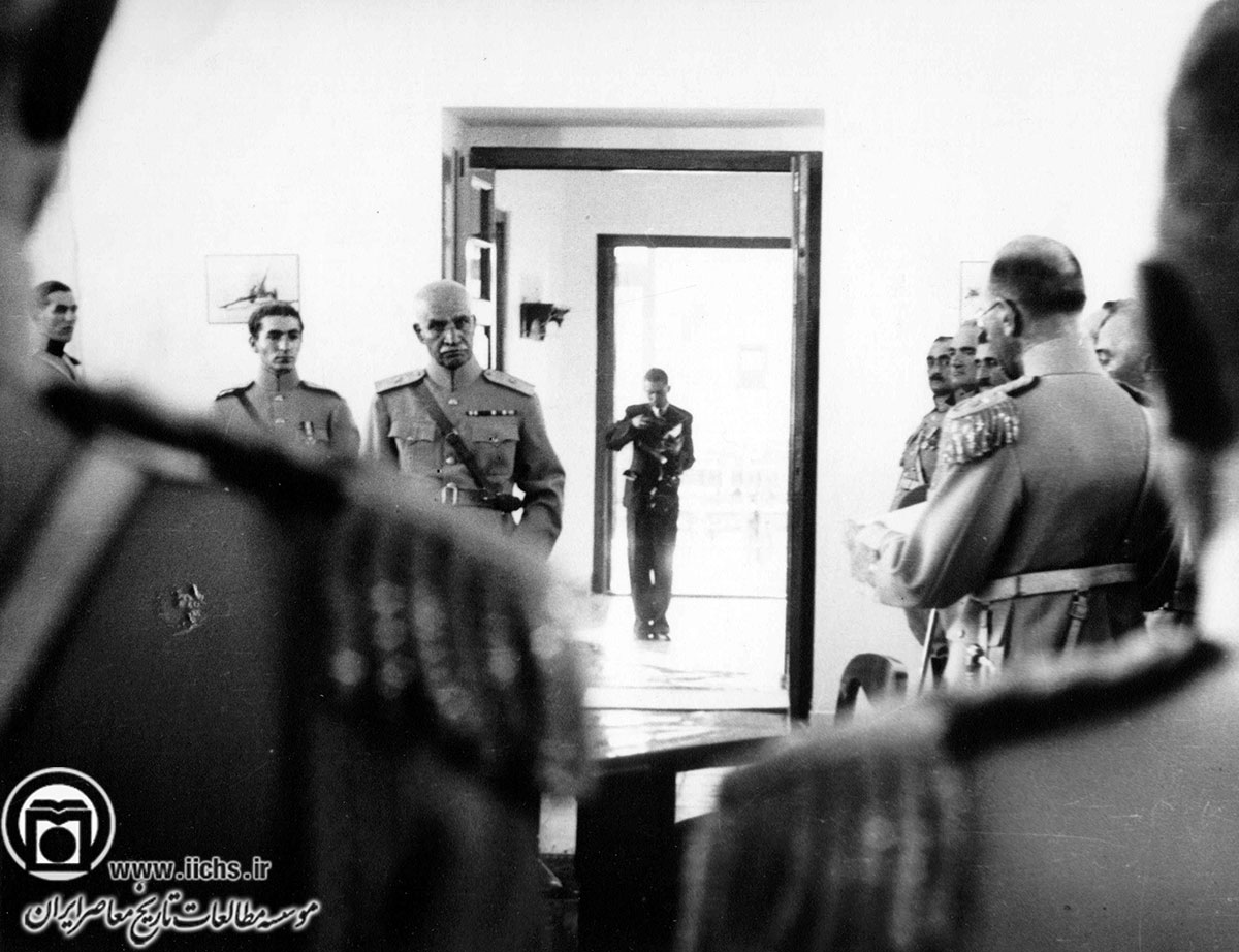 رضاشاه و محمدرضا پهلوی هنگام استماع گزارش عزیزالله ضرغامی (رئیس ستاد ارتش) در مراسم بازدید از دانشگاه جنگ